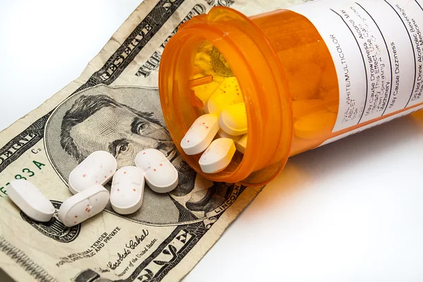Bottle of prescription pills laying on money — Stock Photo, Image