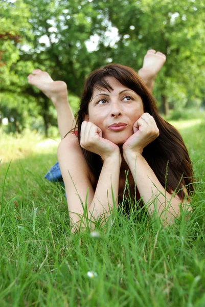 Woman portrait lying in grass dreaming — Stock Photo, Image
