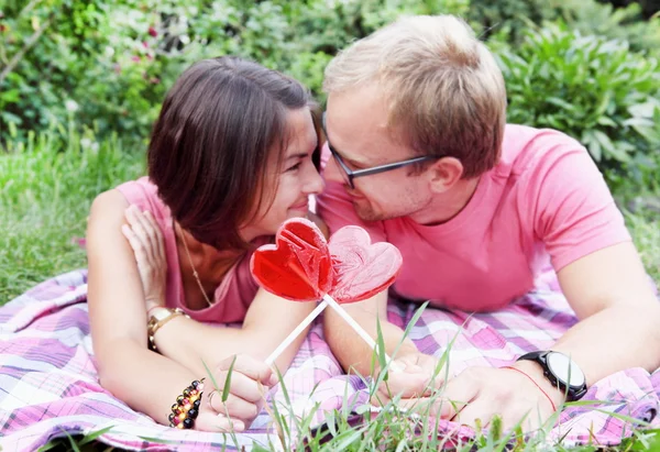 Молодая пара с конфетными сердцами на пикнике — стоковое фото