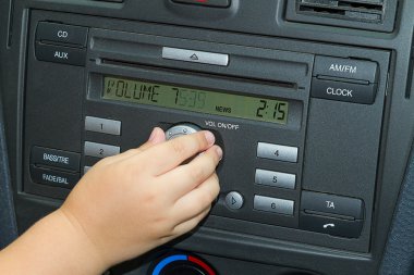 Child adjusts the volume of car radio clipart