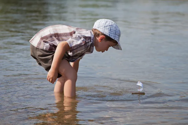Jongen lanceert een kleine zeilboot — Stockfoto