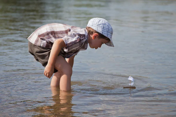 Jongen lanceert een kleine zeilboot Rechtenvrije Stockfoto's