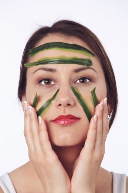 Young woman with her face covered with cucumber slices clipart