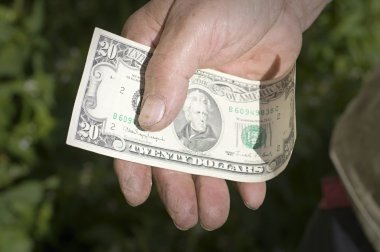 Man's hand holding a twenty-dollar note clipart