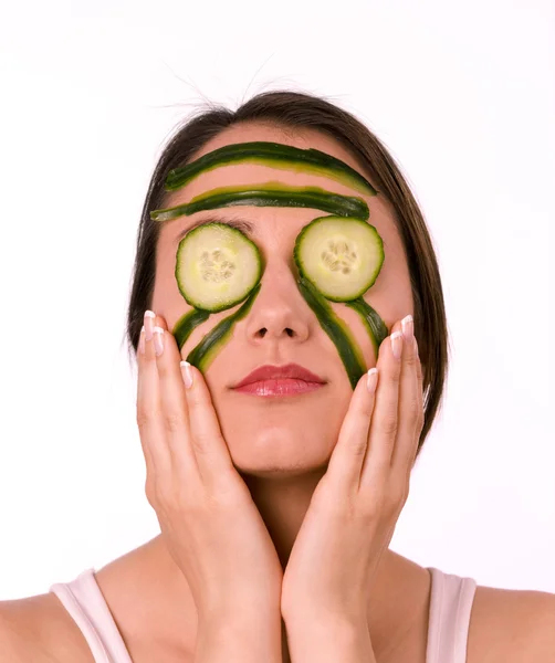 Ung kvinna med hennes ansikte täckt med gurka skivor — Stockfoto