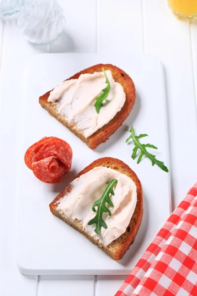Knapperig brood met verspreiding en salami — Stockfoto