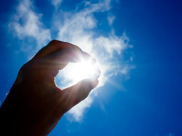 stock image Hand holding coin against sun