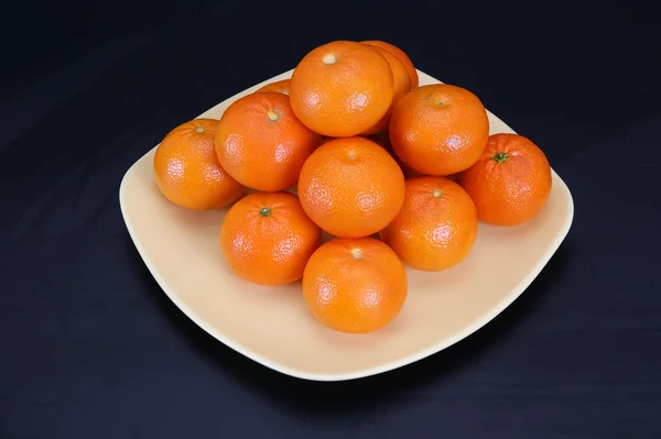 Mandarinas en un plato sobre un fondo negro — Foto de Stock