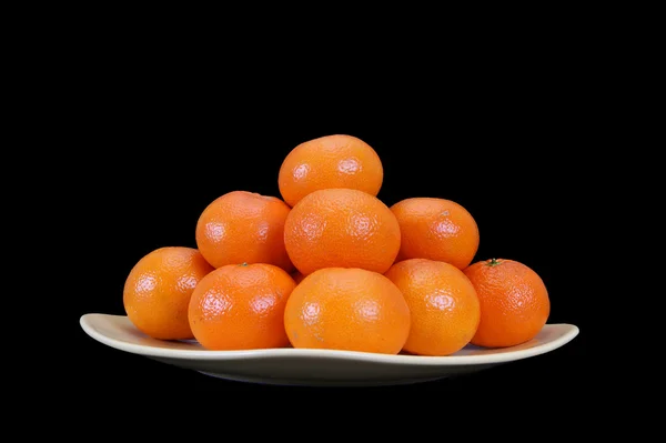 Mandarinas en un plato sobre un fondo negro — Foto de Stock