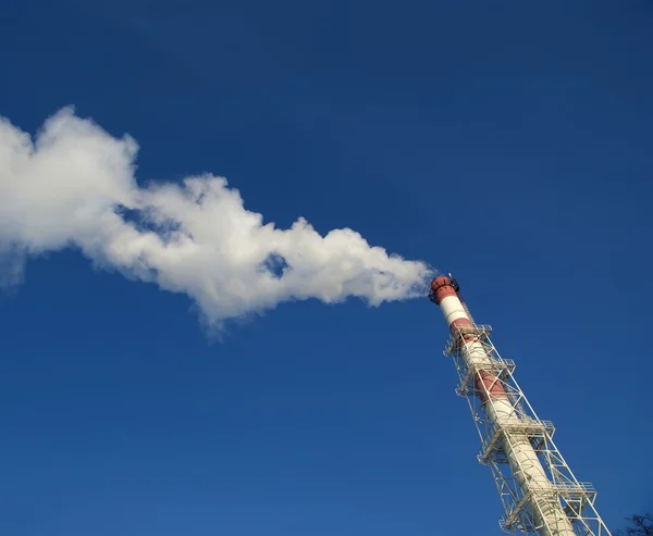 Industrial smokestacks with billowing white smoke being pumped into the atmosphere against a blue sky — Stock Photo, Image