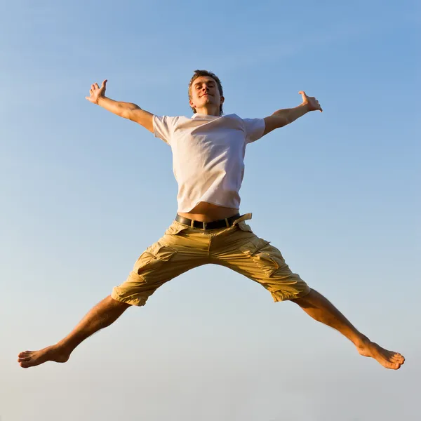 Jovem feliz pulando contra fundo céu azul — Fotografia de Stock