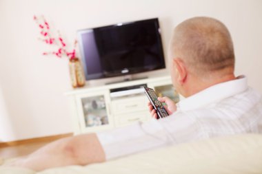 Televiewer on sofa with TV remote control clipart