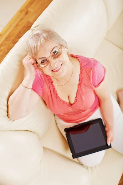 Улыбающаяся женщина дома держит планшетный компьютер — стоковое фото