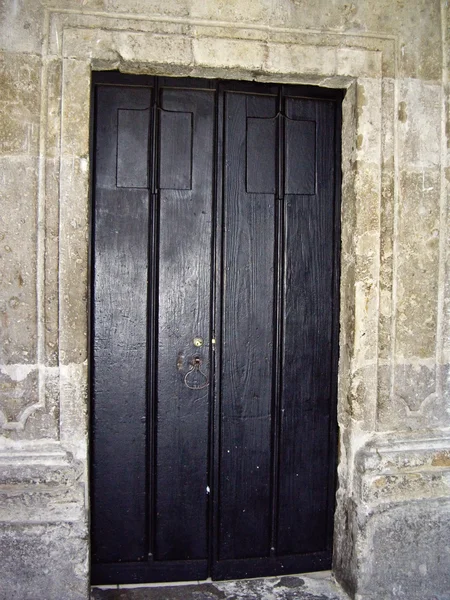 Черная дверь на каменной стене — стоковое фото