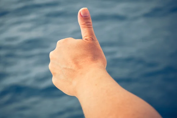 Thumbs up on sea background — Stock Photo, Image