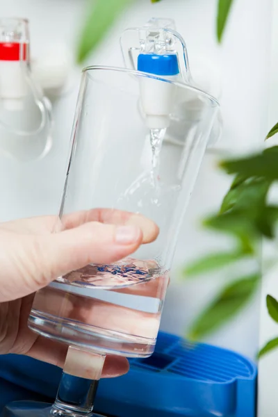 stock image Hand pouring a glass of water from dispenser