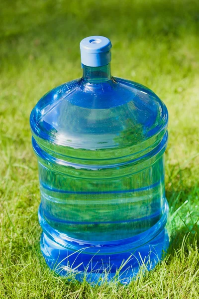 Velká láhev s vodou na zelené trávě pozadí — Stock fotografie