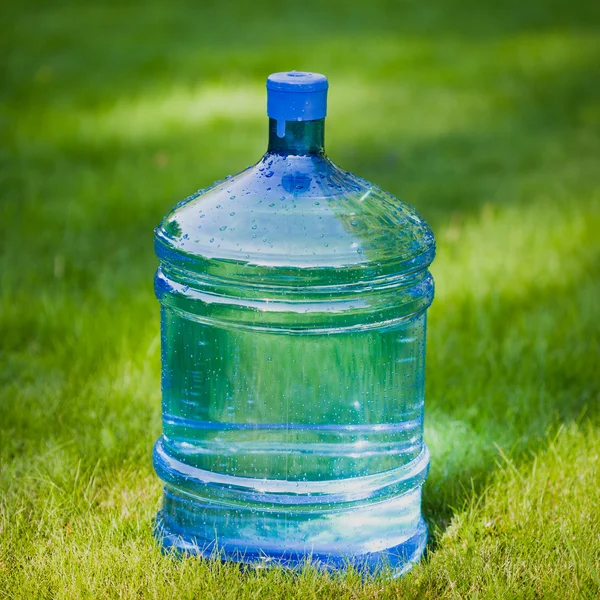 Duża butelka wody na tle zielonej trawie — Zdjęcie stockowe