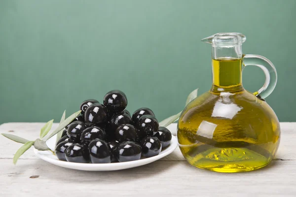 Ein Teller mit schwarzen Oliven und Öl. — Stockfoto