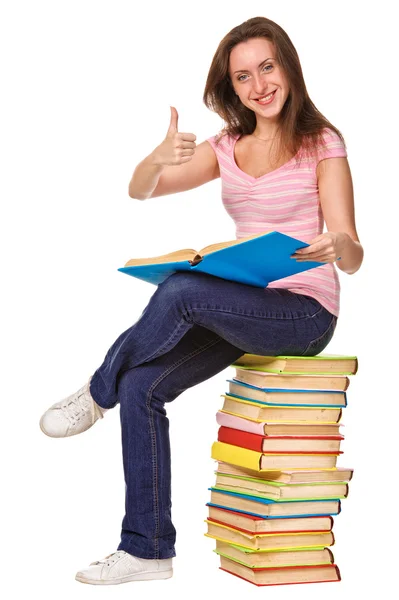 Estudiante sentado en un montón de libros. Pulgar hacia arriba —  Fotos de Stock