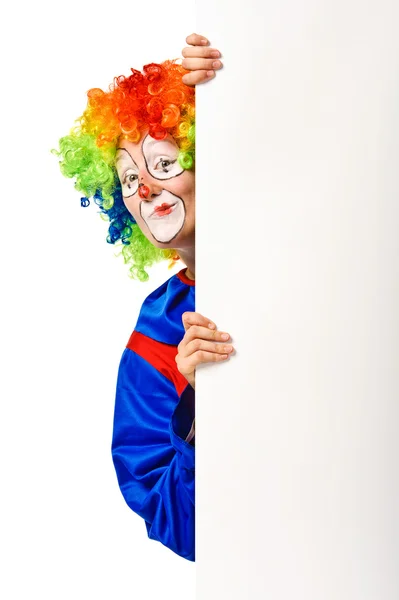 Joyeux clown jetant un coup d'oeil à partir du tableau blanc vierge — Photo