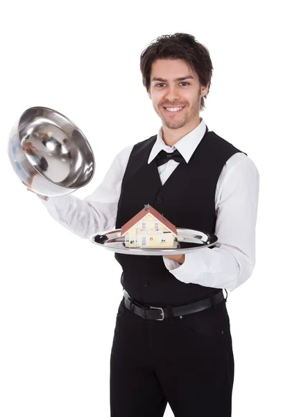 Porträtt av en butler med modell av ett hus — Stockfoto