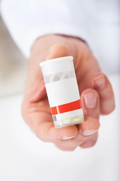 Dottore in possesso di un contenitore pillola in farmacia — Foto Stock