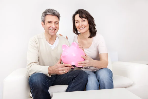 Älteres Ehepaar spart Geld in Sparschwein — Stockfoto