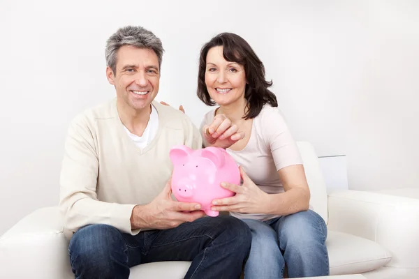 Mature couple saving money in piggybank — Stock Photo, Image