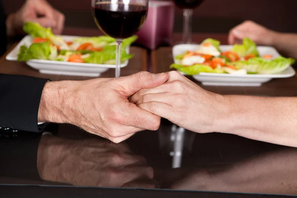 Трогательные руки за романтическим ужином в ресторане — стоковое фото