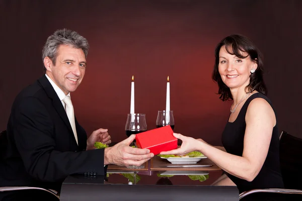 Мужчина дарит подарок женщине в ресторане — стоковое фото