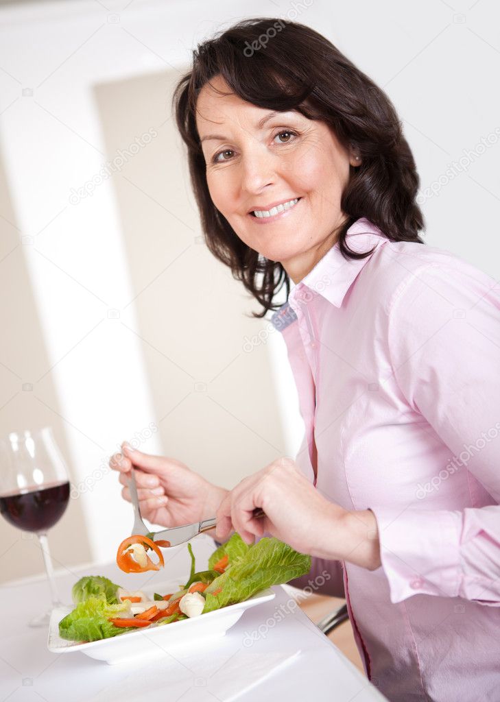 Mature woman having lunch at home