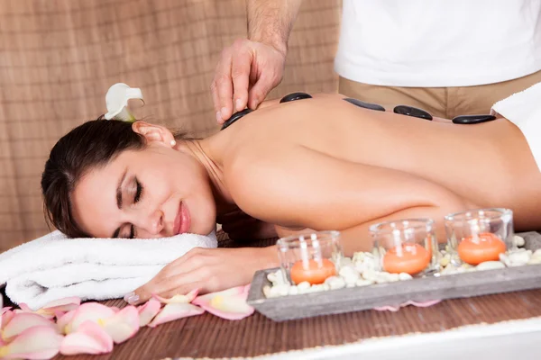 Beautiful young woman getting hot stone therapy — Stock Photo, Image