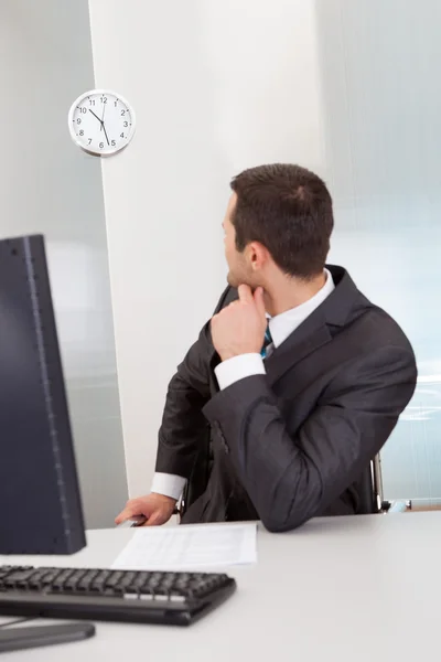 Businessman looking at clock at the office — Stock Photo, Image