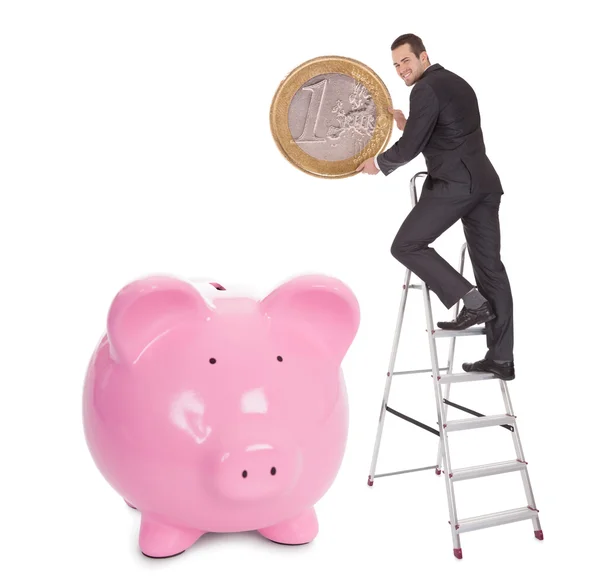 Businessman putting one euro coin into piggybank — Stock Photo, Image