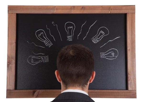 Businessman standing in front on blackboard — Stock Photo, Image