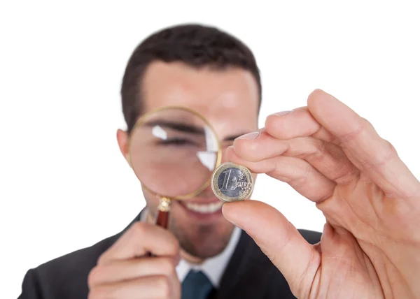 Geschäftsmann betrachtet Ein-Euro-Münze durch Lupe — Stockfoto