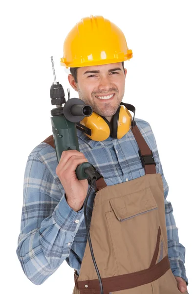 Рабочий держит дрель и носит каску — стоковое фото