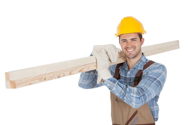 Worker wearing hard hat and carrying timber — Stock Photo, Image