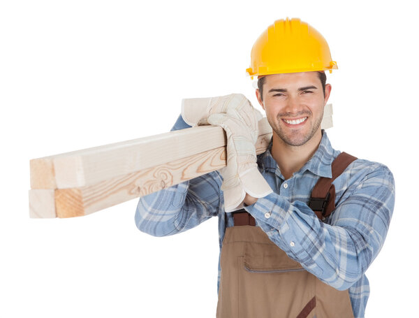 Worker wearing hard hat and carrying timber