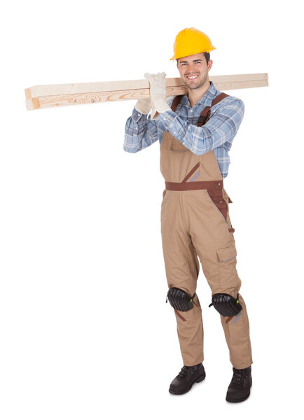 Worker wearing hard hat and carrying timber