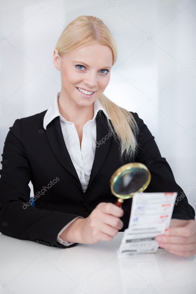Businesswoman looking at check trough the loupe
