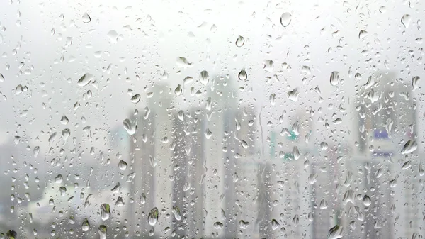 Hujan turun pada kaca dengan latar belakang kota — Stok Foto