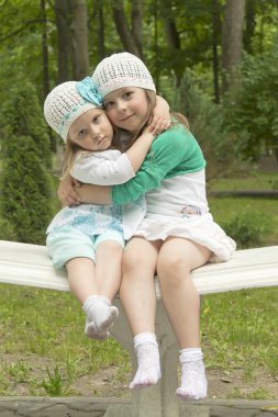 Sisters in park on a bench clipart