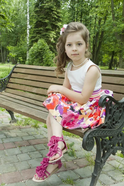 伤心的女孩坐在公园的长凳上， — 图库照片