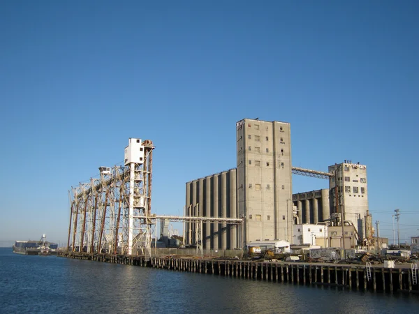 Large old rundown cement factory along the water — Stock Photo, Image