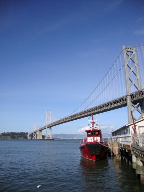 Fireboat docked in front of the San Francisco-Oakland Bay Bridge clipart