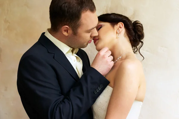 Groom kisses bride in empty room — Stock Photo, Image