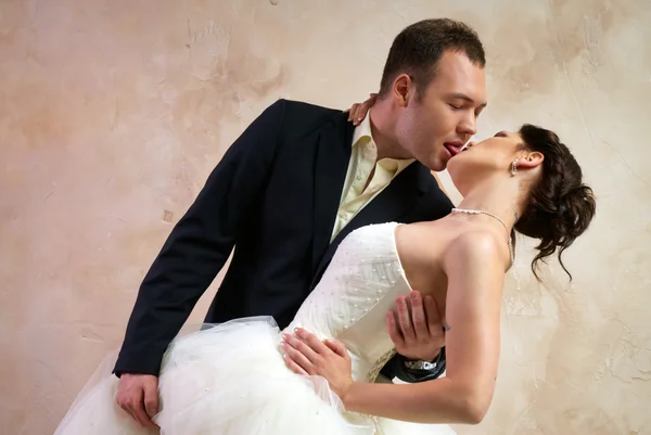 Brudgummen kysser bruden i tomma rum — Stockfoto