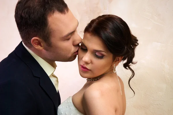 Bräutigam küsst Braut im leeren Zimmer — Stockfoto